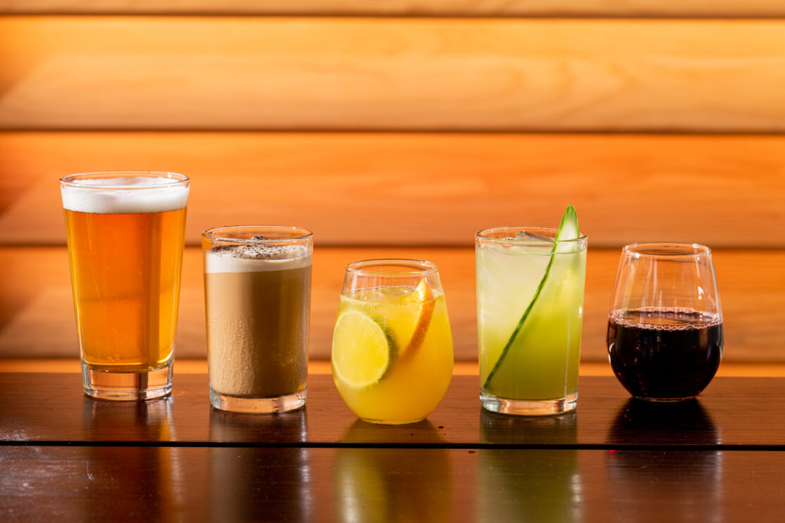 A table topped with glasses filled with different types of beer, wine, and cocktails.