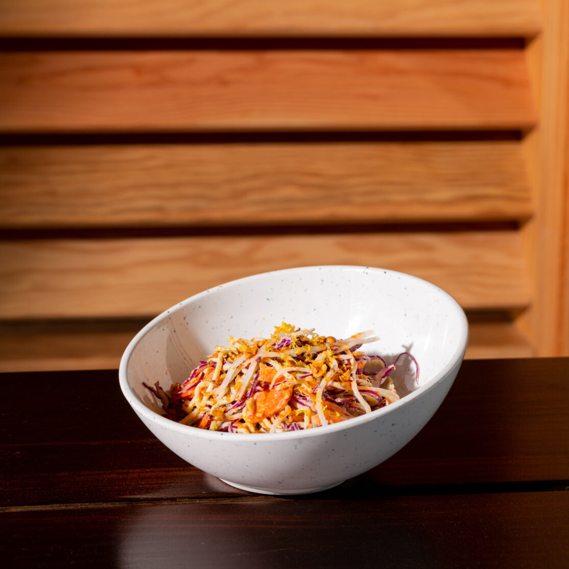 A close-up of chilled ginger noodle salad served in a white bowl.