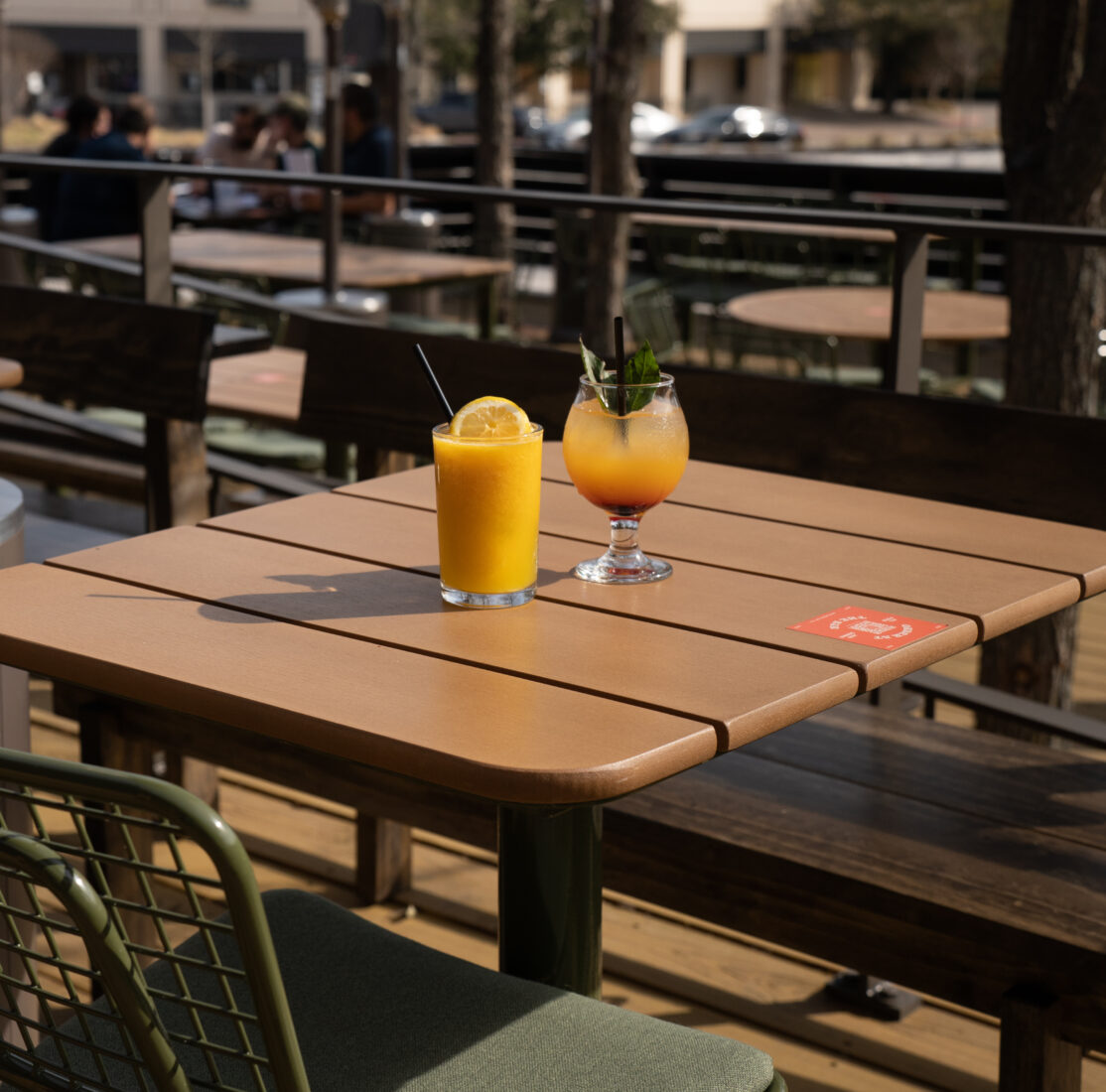 A boozy slushee and a typhoon cocktail sitting on a wooden table.