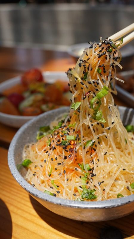 A close-up of sesame rice noodles served in a gray bowl.