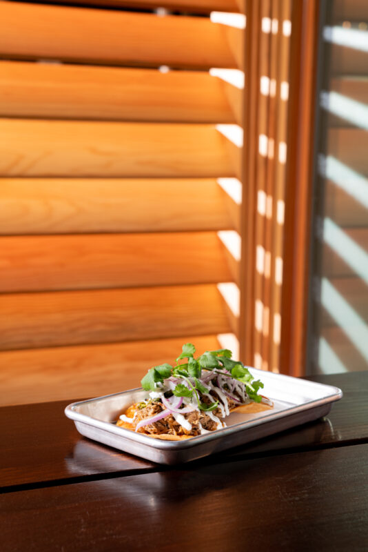 Pulled pork tostadas served on a metal tray.