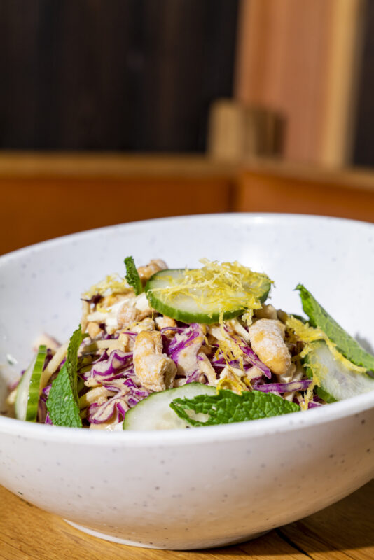 A close-up of a crunchy cabbage salad served in a white bowl.