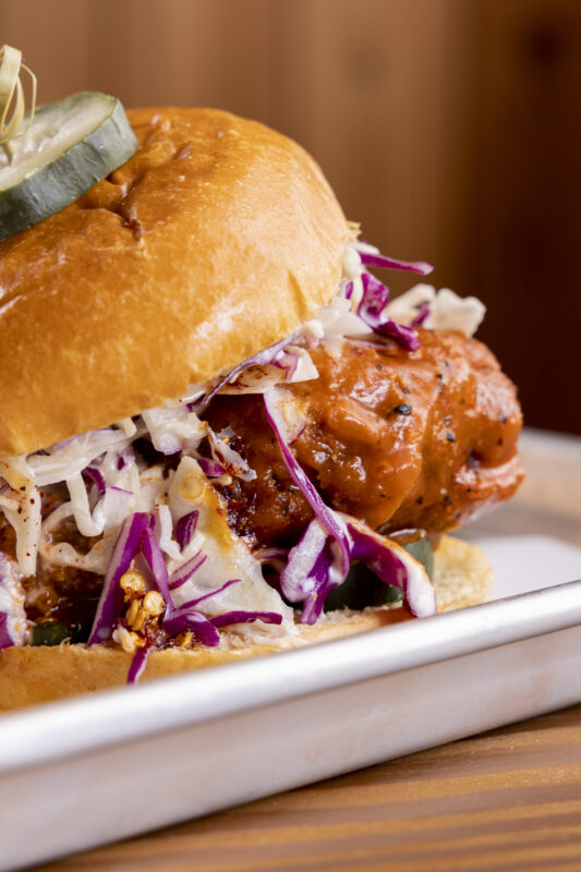 A close-up of a crispy chicken sandwich served on a metal tray.