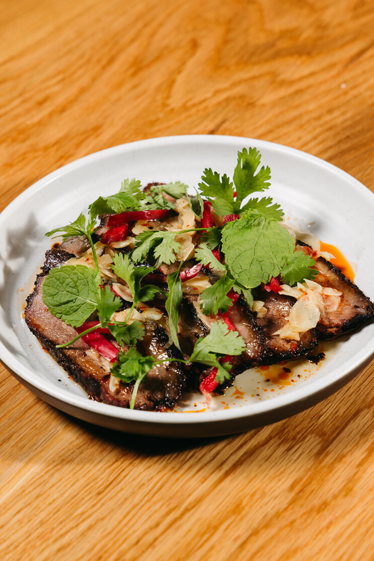 plate of smoked beef brisket topped with thai herbs