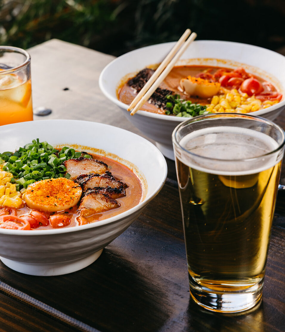 side view 2 bowls of spicy Japanese curry ramen with a glass of beer