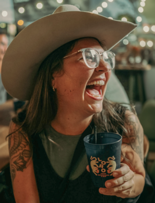 Woman wearing a cowboy hat holding a cocktail