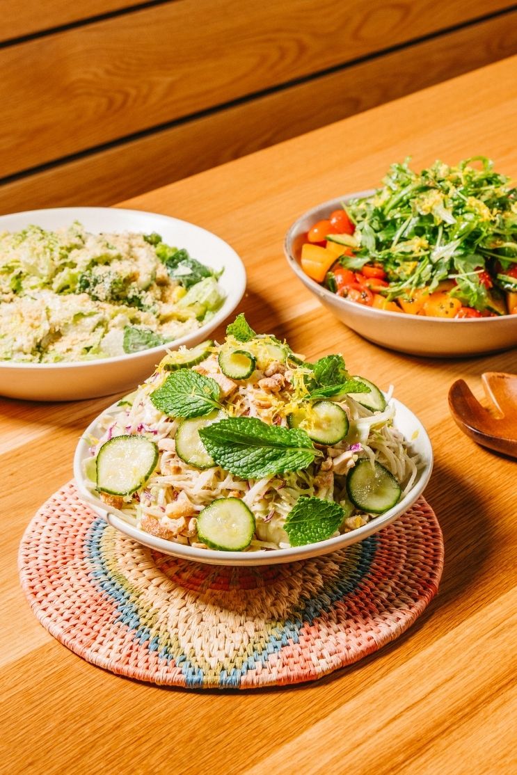 cabbage salad, loro cesar salad, and arugula melon salad in white bowls