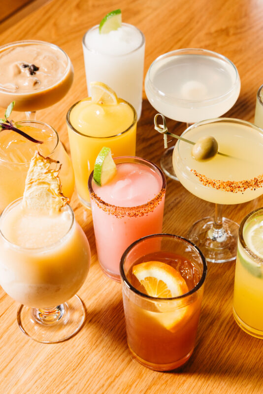 group of colorful cocktails on a wooden table