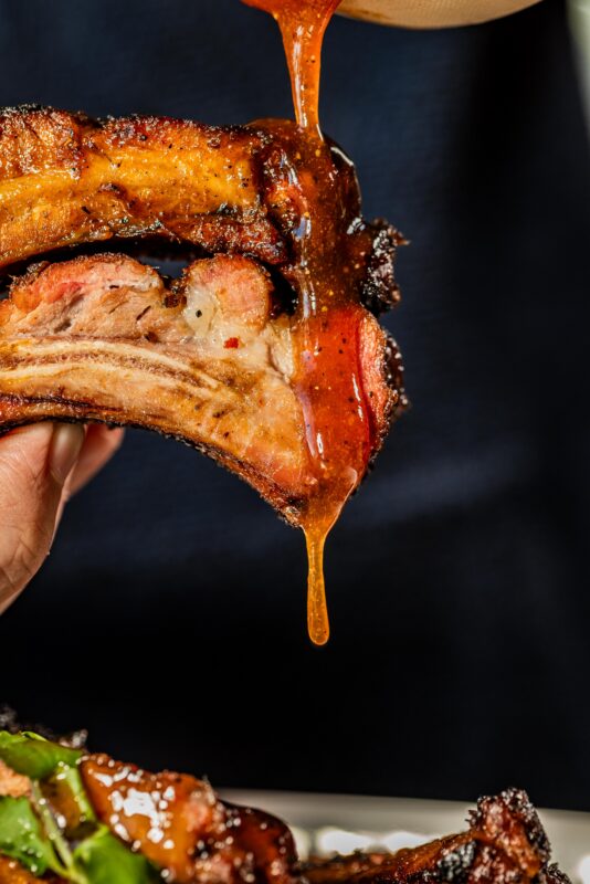 two smoked pork ribs dripping in bbq sauce